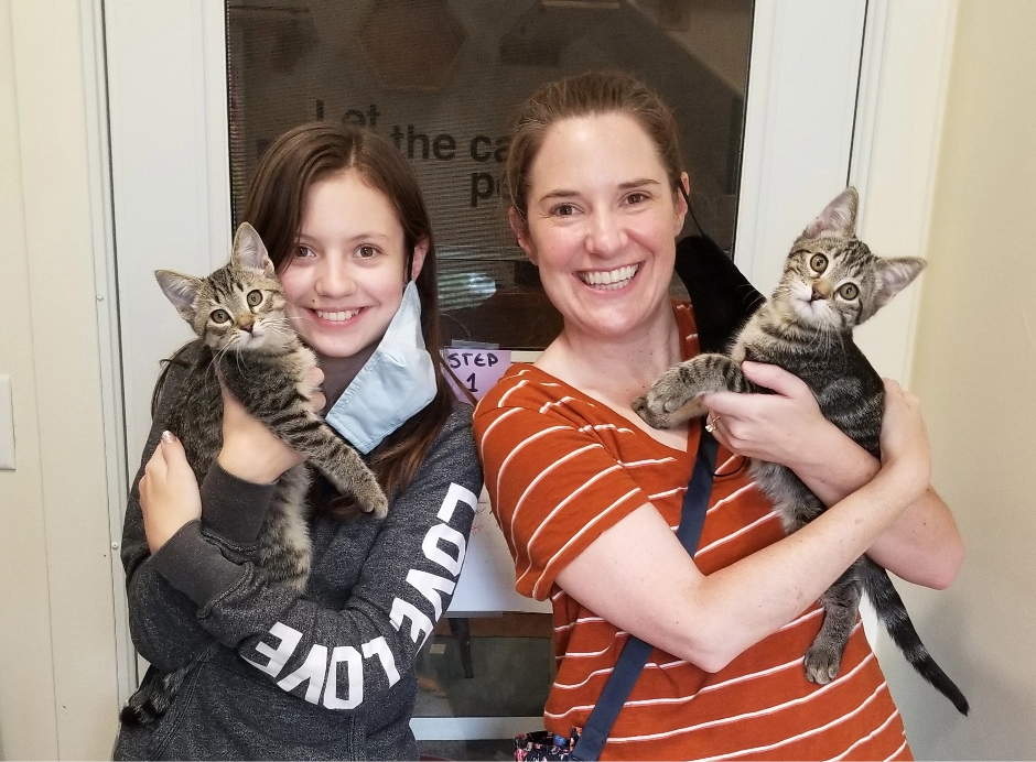 two new owners hold cats at Happy Cats Haven, a cat rescue in Colorado Springs